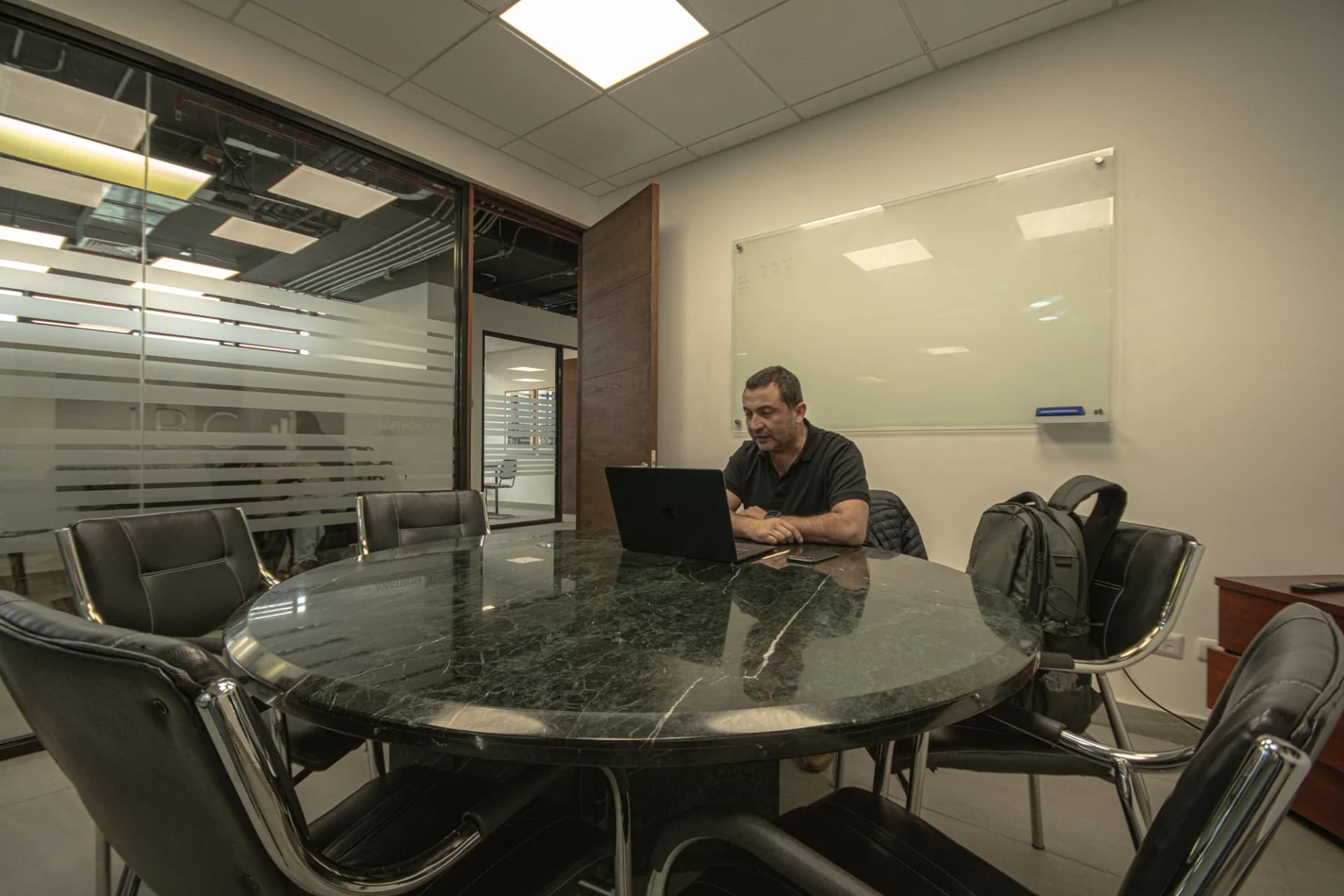 Sala Montaña: mesa redonda para seis personas con pizarrón de vidrio